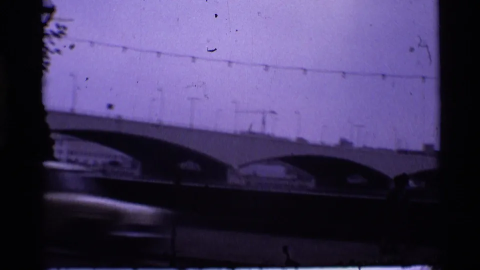 1969 London 8mm view of a multi-arched bridge with lamps above and a blurred vehicle moving through the lower foreground.