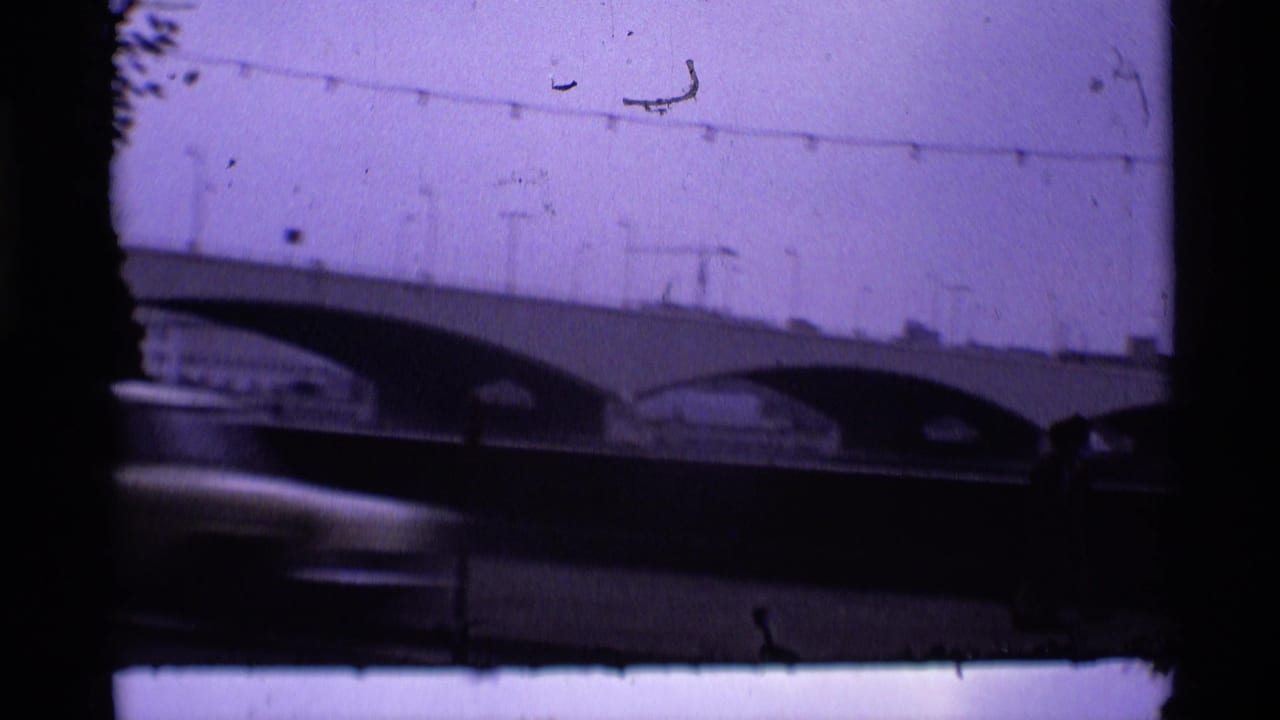 1969 London 8mm frame showing a low view of an arched bridge over water, with silhouetted figures and a purple color cast.