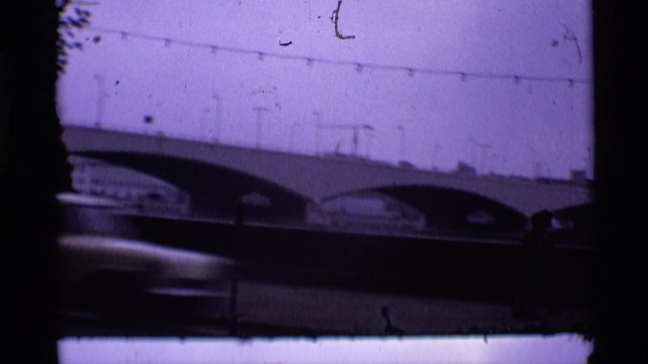 Arched bridge over a dark roadway with a blurred vehicle crossing the foreground.