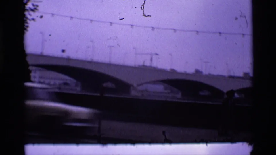 1969 London home-movie frame showing an arched bridge and railing through a dark, slightly soft 8mm frame.