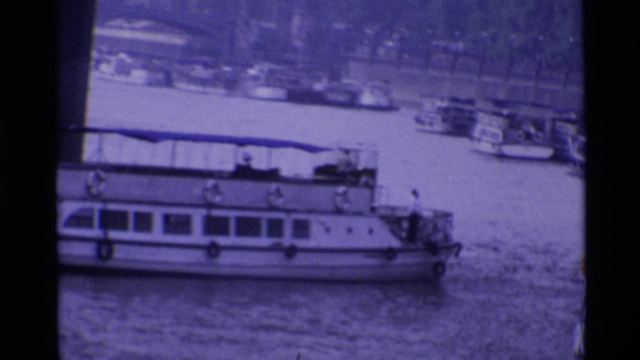1969 London 8mm frame showing a large white riverboat passing near moored boats on the river.