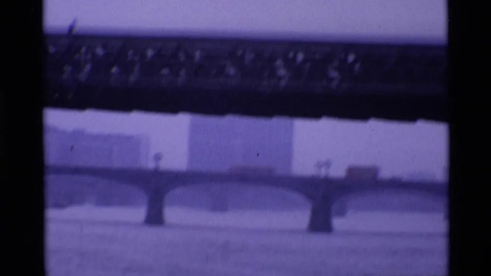 1969 London 8mm frame looking toward a stone arch bridge over the river from beneath a darker bridge element.