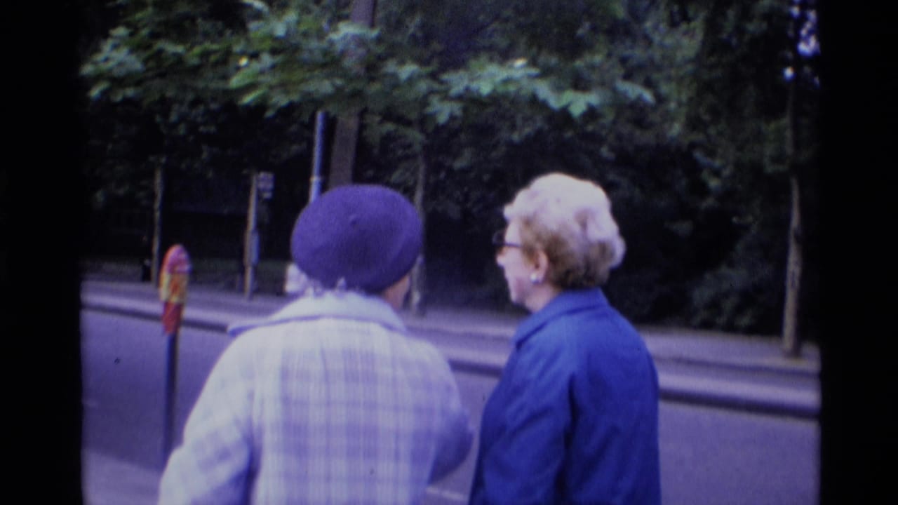 Two women seen from behind beside a tree-lined road.