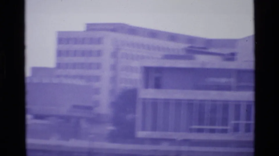 1969 London frame showing layered modernist buildings, a tall background block, and a low foreground facade.