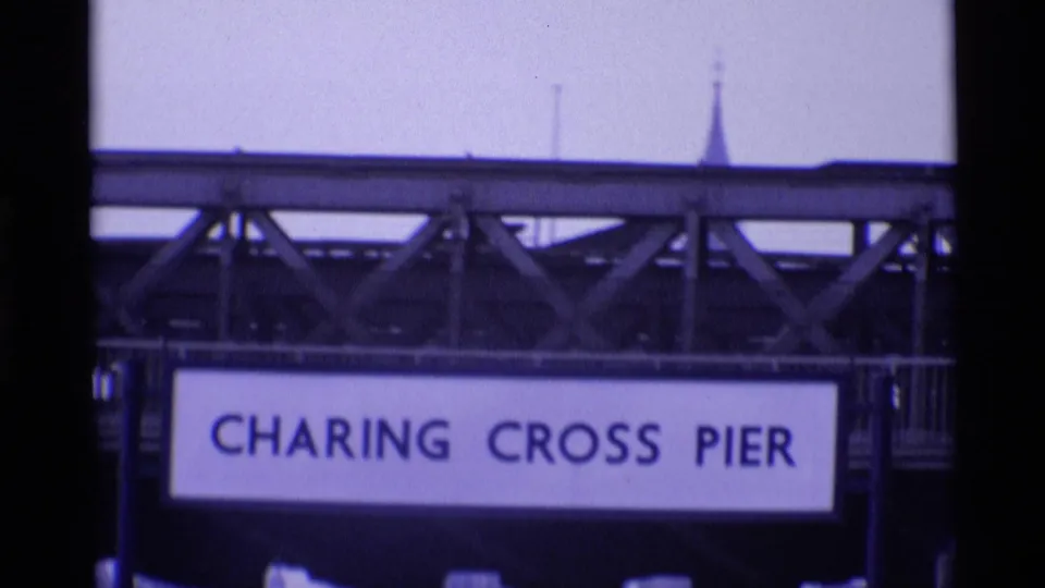 Close view of the Charing Cross Pier sign beneath a steel bridge span in London, with soft focus and purple 8mm color cast.