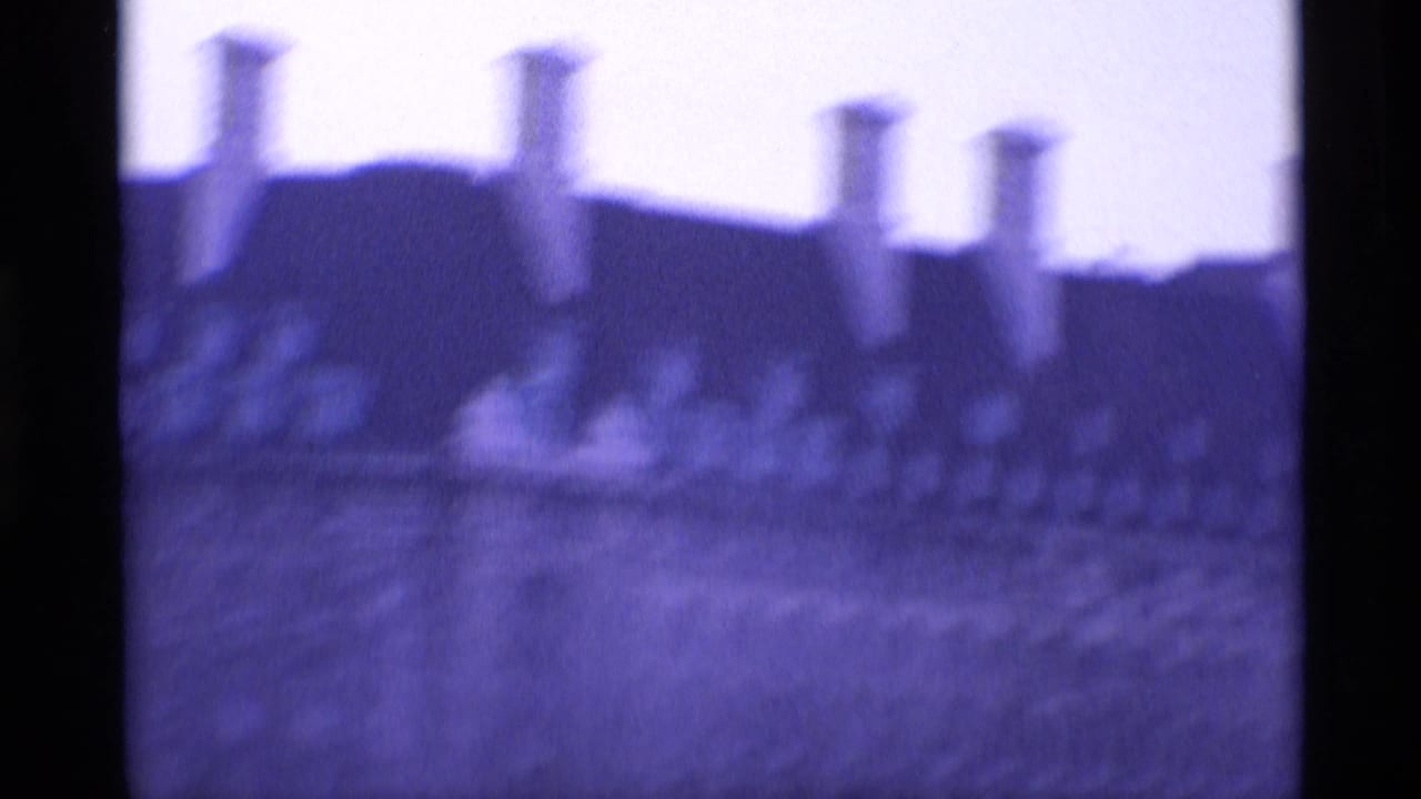 1969 London 8mm frame showing a blurred ornate building roofline with multiple chimneys and heavy purple film tint.