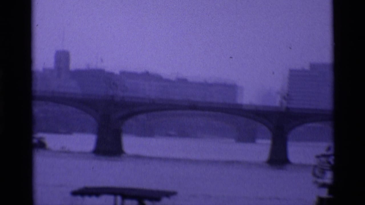 1969 London 8mm frame showing the River Thames, a long arched bridge and hazy riverside buildings at dusk.