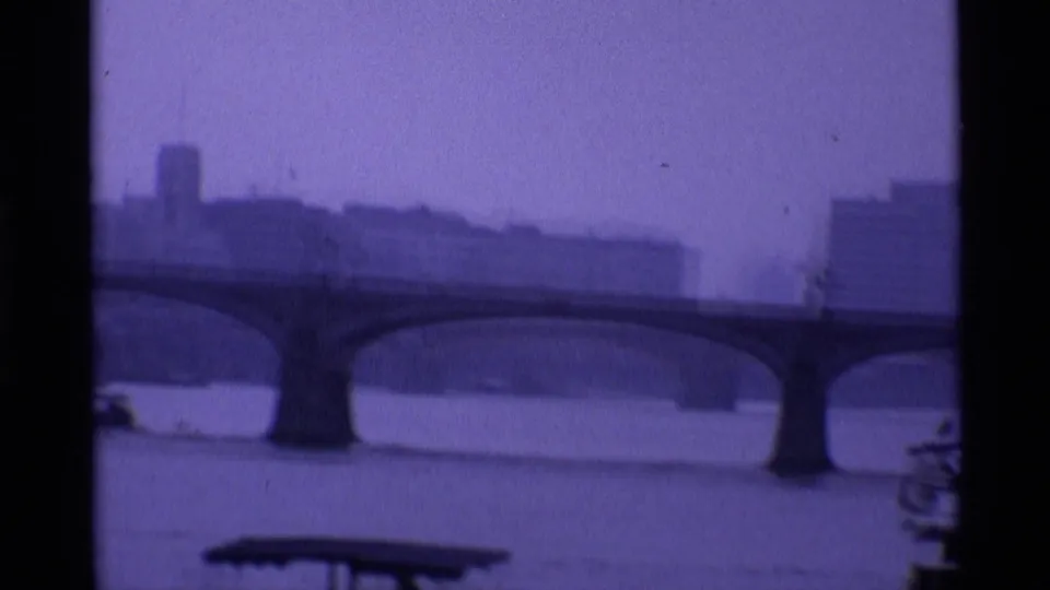 1969 London 8mm frame showing the River Thames, a long arched bridge and hazy riverside buildings at dusk.