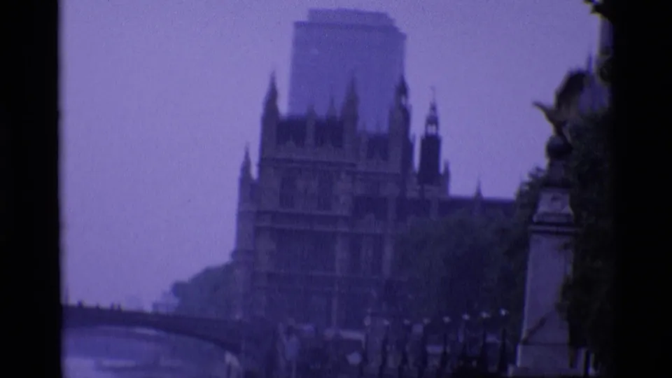 1969 London frame showing the Houses of Parliament, a Thames bridge and riverside trees under a purple dusk cast.