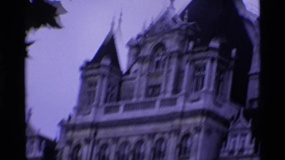 1969 London 8mm frame showing an ornate pale building corner with pointed spires, arched windows, and heavy soft-focus blur.