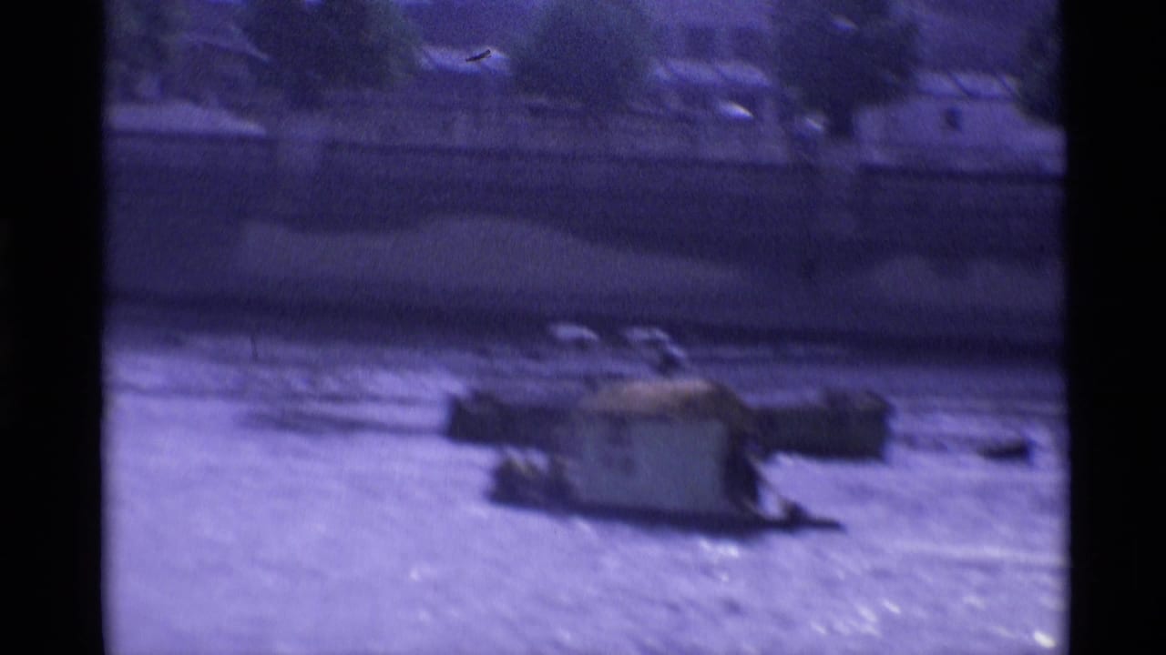 1969 London home-movie frame showing a small cabin boat on river water, with soft focus and a dark border from the film scan.