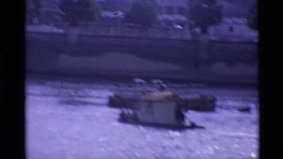 1969 London home-movie frame showing a small cabin boat on river water, with soft focus and a dark border from the film scan.