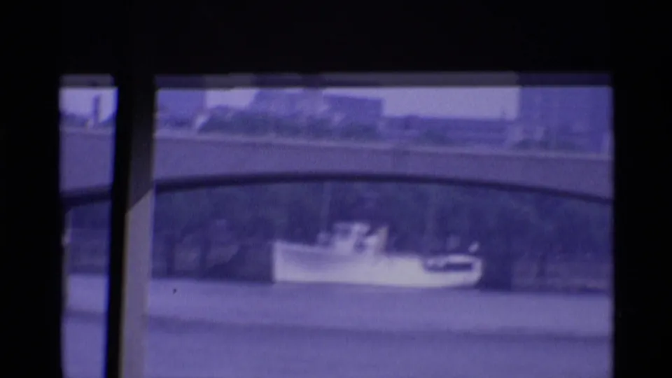 1969 London 8mm frame showing the small river boat again, with a stone bridge and distant embankment visible through faded color.