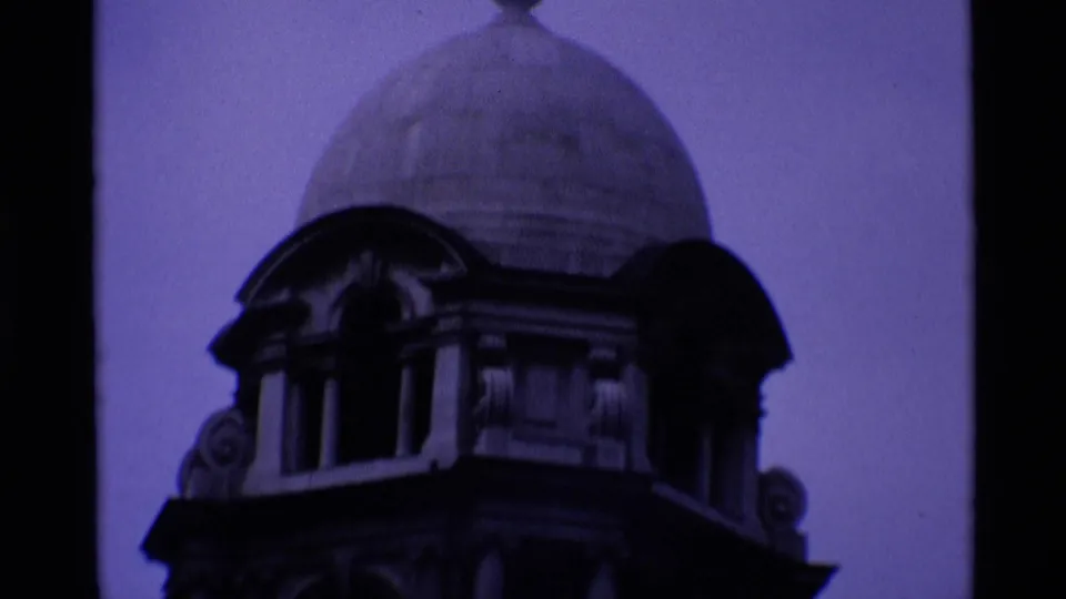 1969 London 8mm frame showing a dark domed architectural feature or tower detail against a blue-purple sky.
