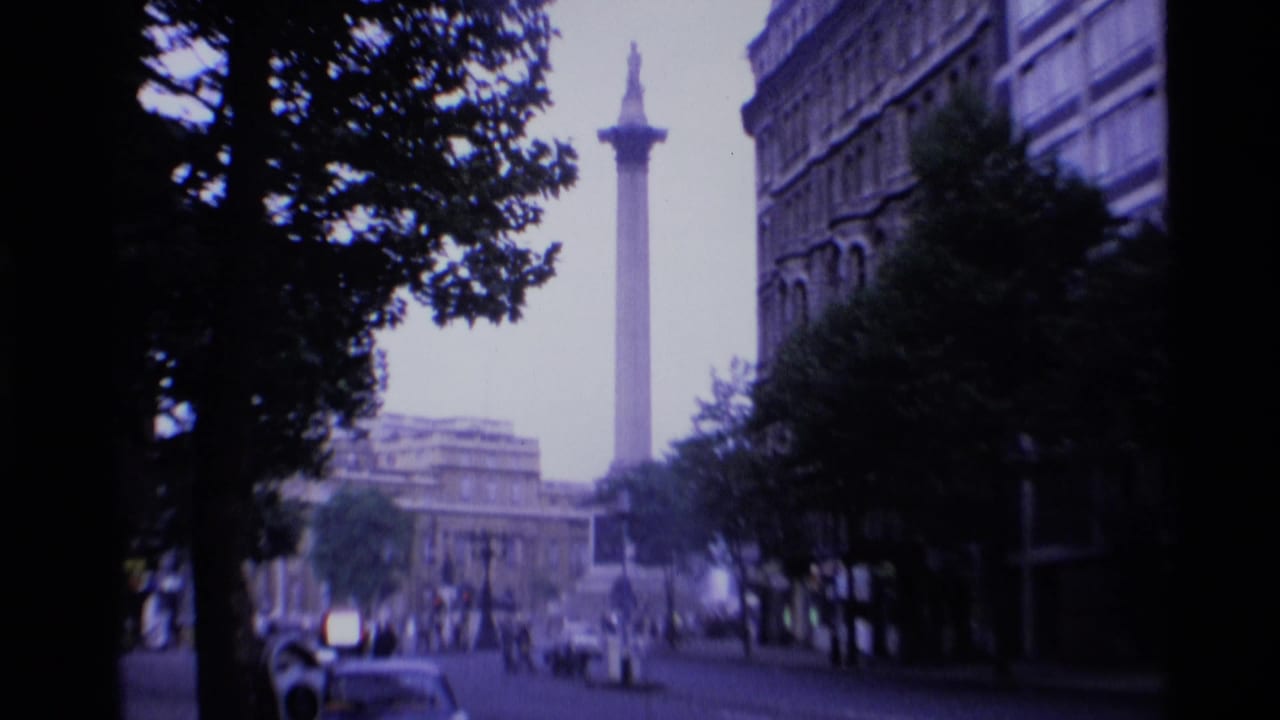 Nelson's Column rises beyond trees and city buildings in a handheld 1969 London street view.