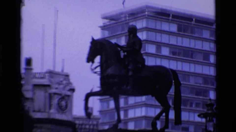 1969 London frame with a silhouetted equestrian statue set against modern office buildings and pale sky.