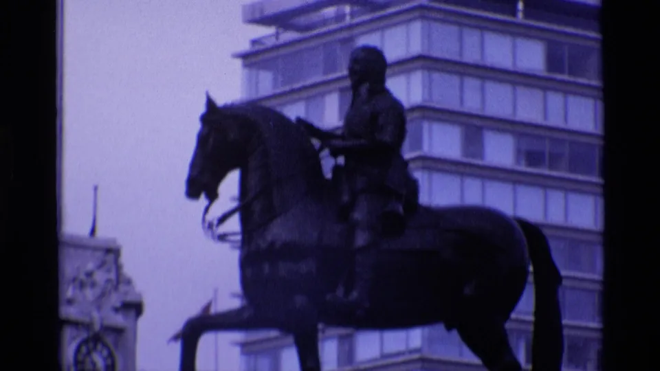 1969 London 8mm frame showing an equestrian statue in front of mid-century buildings with a strong purple-blue film cast.