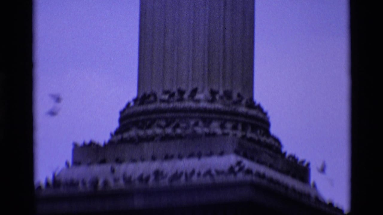 Blue-toned 1969 8mm frame from London showing the decorated base and lower shaft of a monumental column.