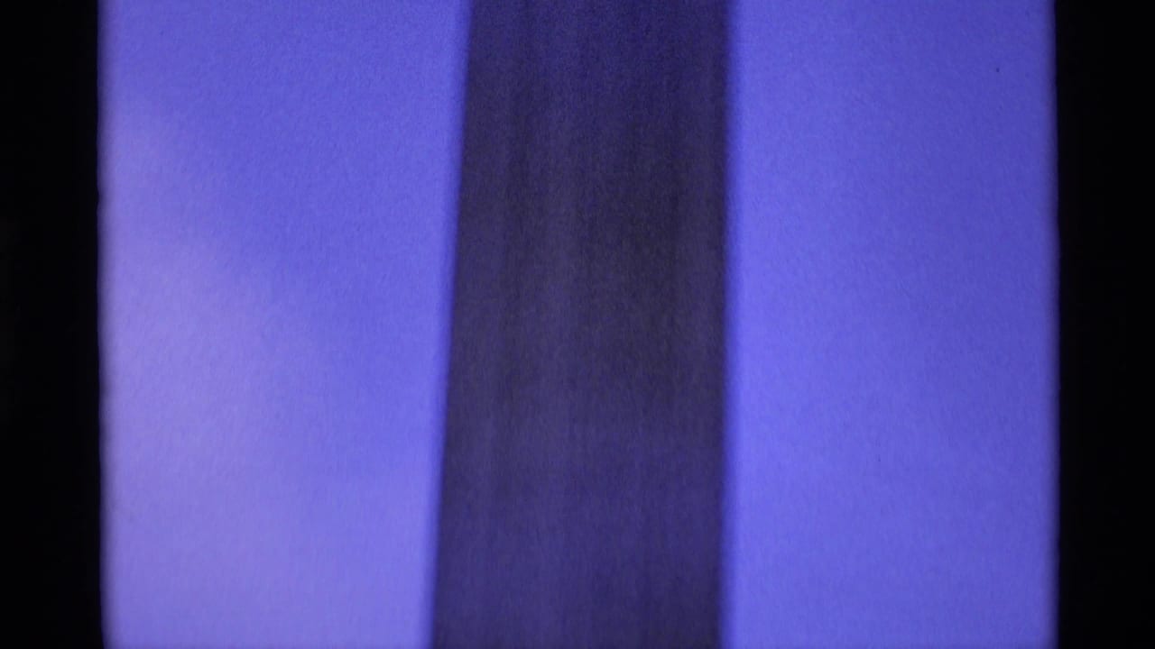Blue-toned 1969 London home-movie frame showing a close vertical section of a monument column.