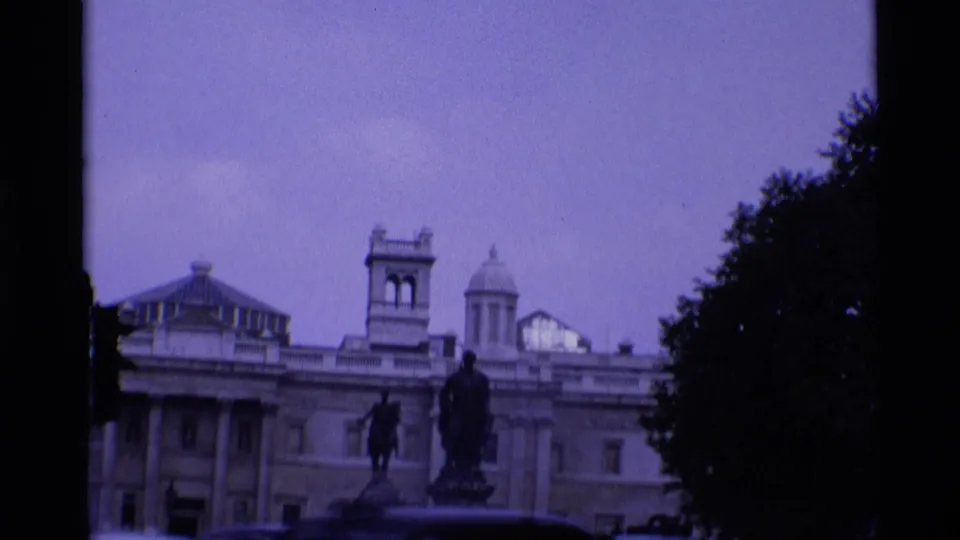 London Trafalgar Square frame showing the National Gallery roofline, a statue, open sky, and a tree silhouette.