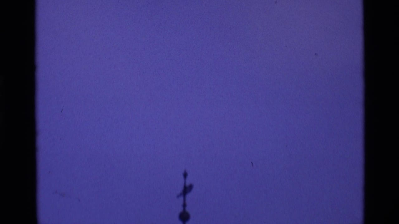 A silhouetted church spire or rooftop ornament appears against a deep purple London sky in 1969 8mm footage.