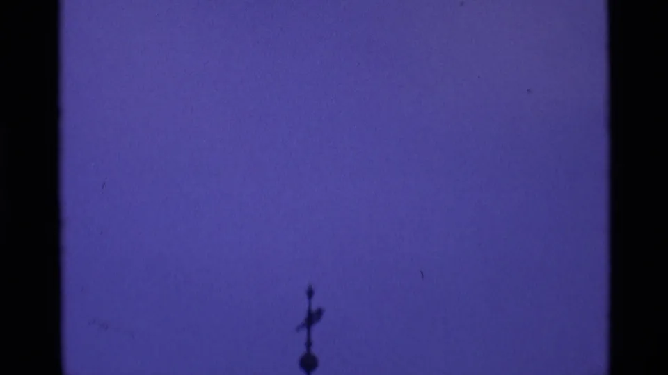 A silhouetted church spire or rooftop ornament appears against a deep purple London sky in 1969 8mm footage.