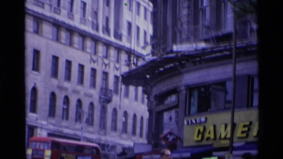 A 1969 London street view shows tall facades, a red double-decker bus, and a large camera-shop sign partly visible.