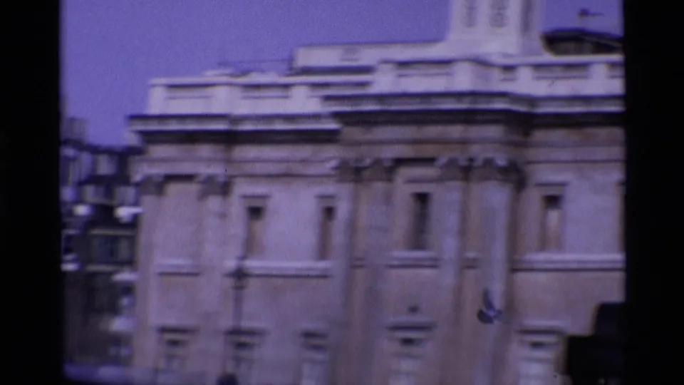1969 London architectural cutaway showing a pale stone facade, windows, and roof detail in soft 8mm footage.
