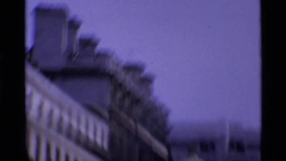 Soft, blurred 8mm view of London building facades and pale sky, likely captured during a quick handheld camera movement.
