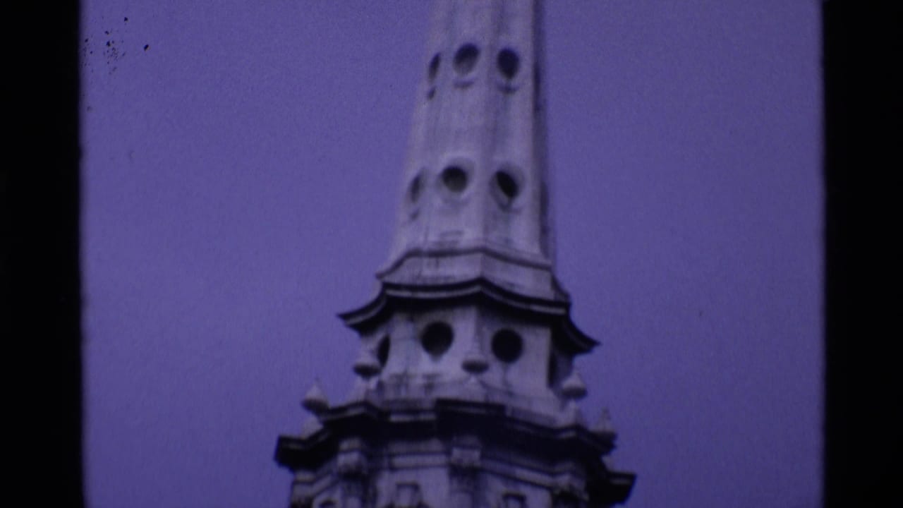 Ornate stone spire and upper tower section against a blue-purple sky.