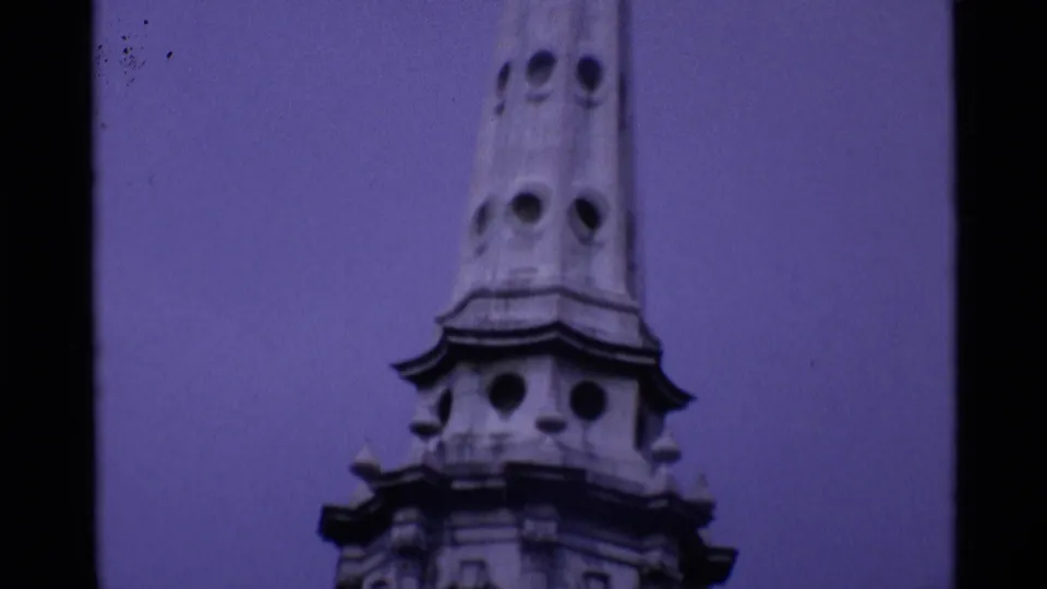 Upper section of a London historic tower or spire, filmed in 1969 with soft grain and a purple-blue film cast.