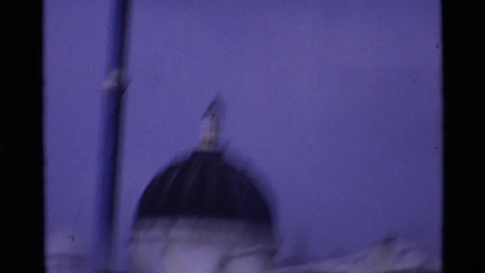 Soft handheld 1969 London frame showing a dark dome, rooftop detail, and vertical pole during the camera pan.