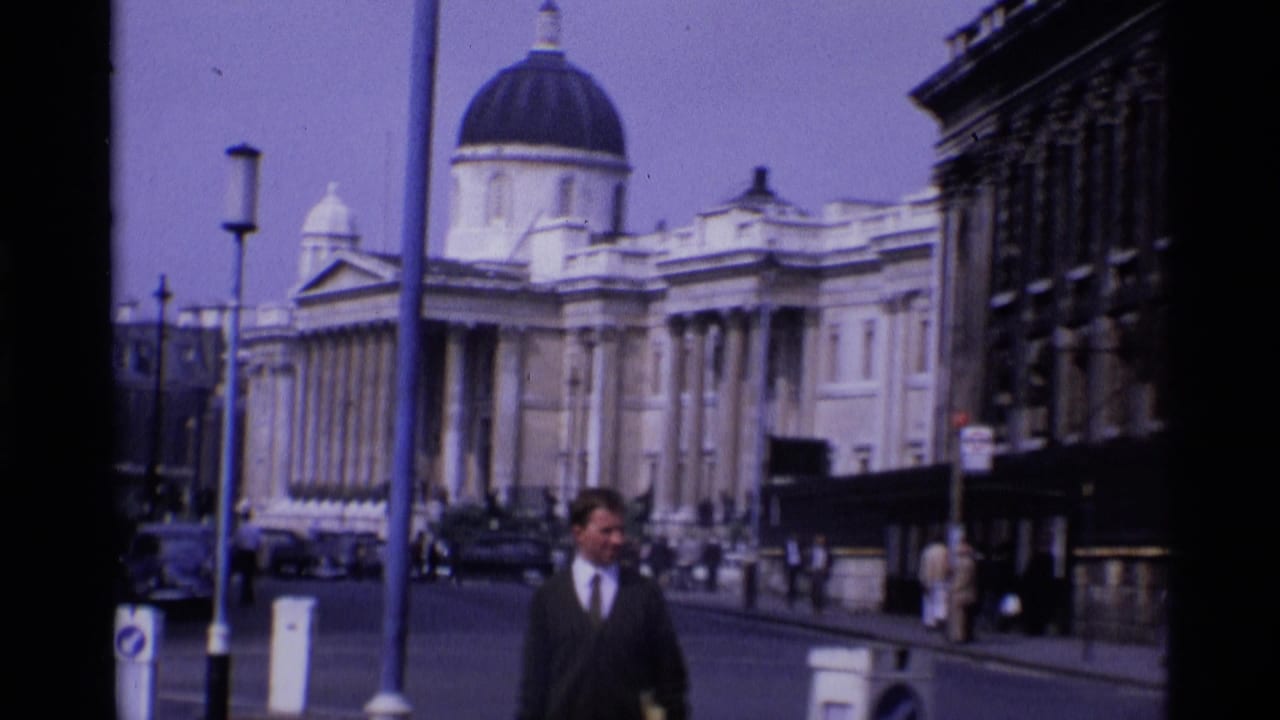 Busy street with a domed building, pedestrians, cars, and a man in a dark suit.