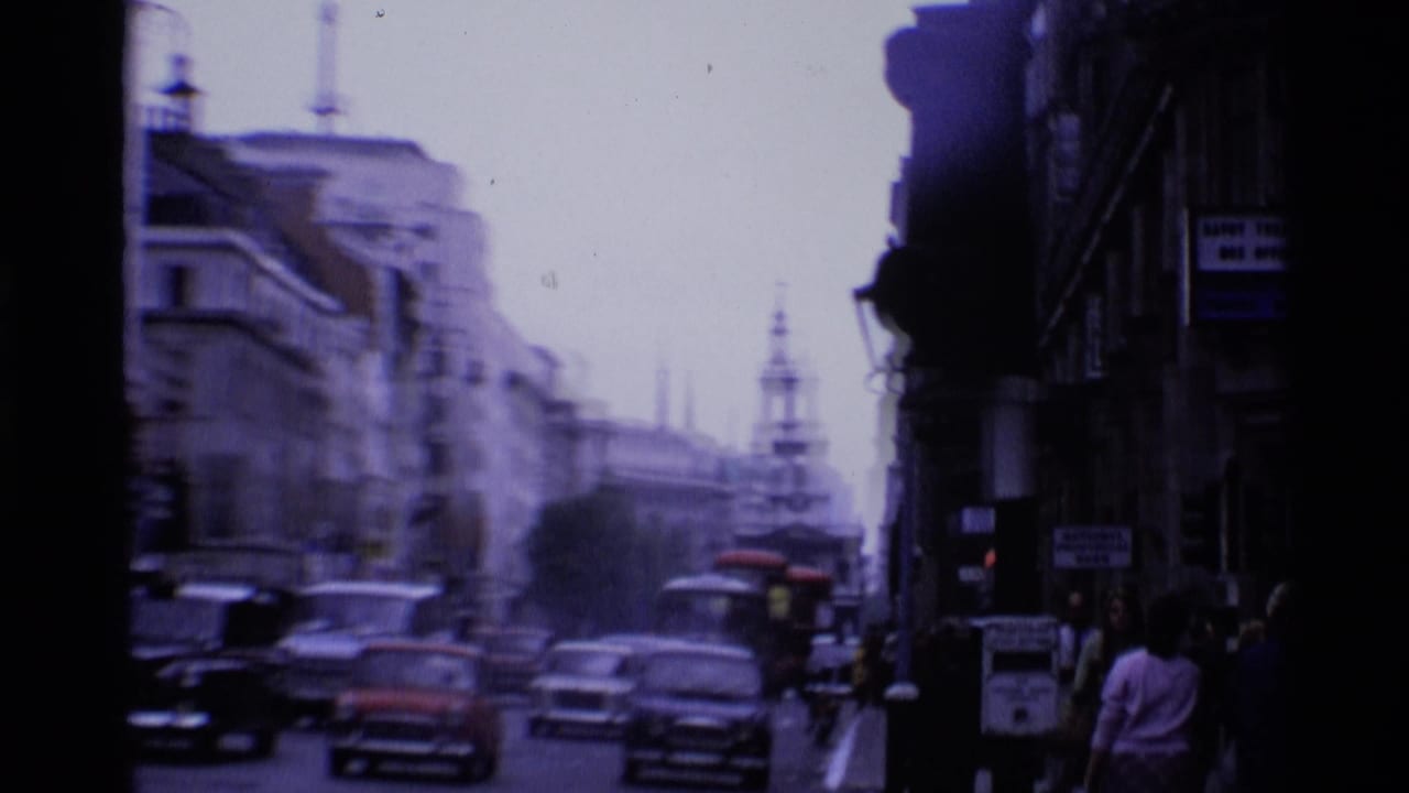 1969 London street scene with classic cars, pedestrians, tall buildings, and a distant spire under an overcast sky.