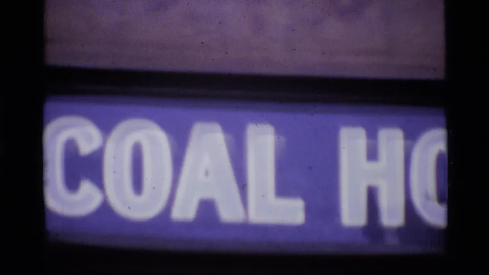 1969 London frame showing blurred shop signage with partial lettering below traffic and buildings in the upper view.