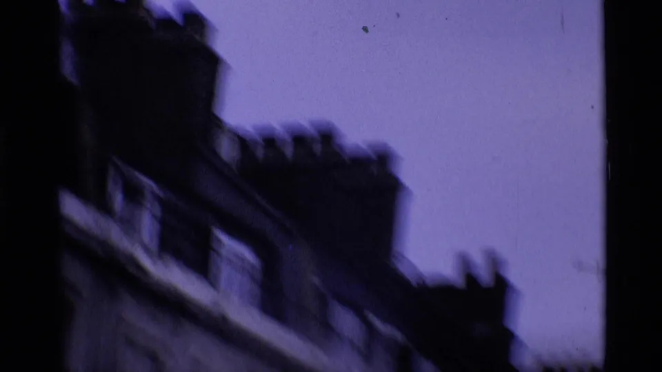 Blurred 1969 London home-movie view of sloping rooftops and chimney stacks during a handheld movement.