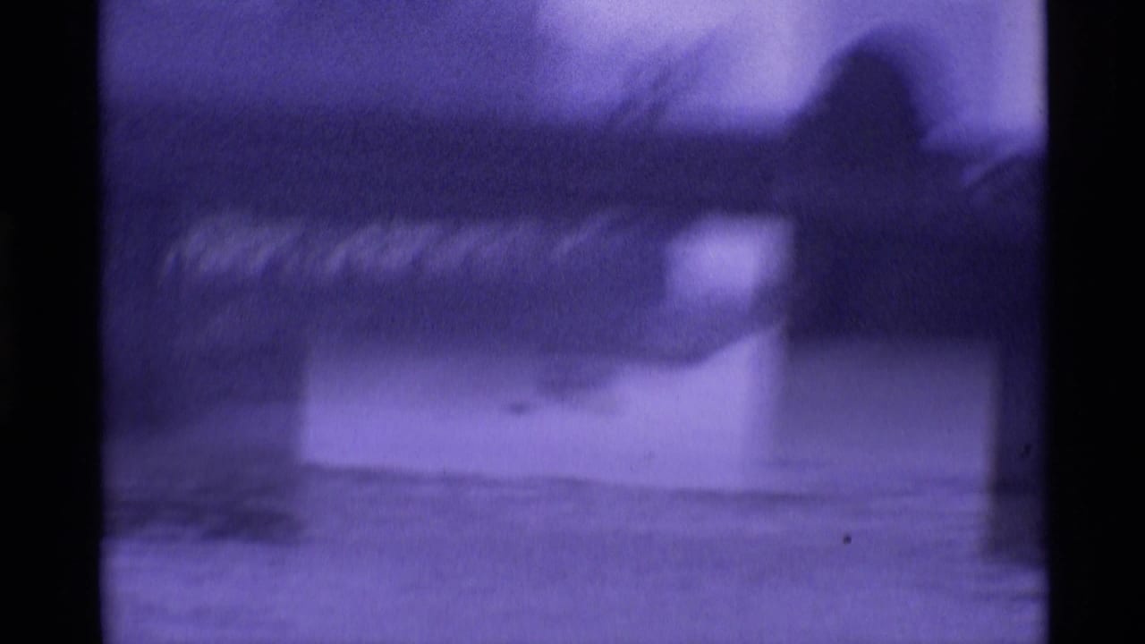 1969 London 8mm frame showing a hazy River Thames view beneath or near a bridge, with soft focus and dark film edges.
