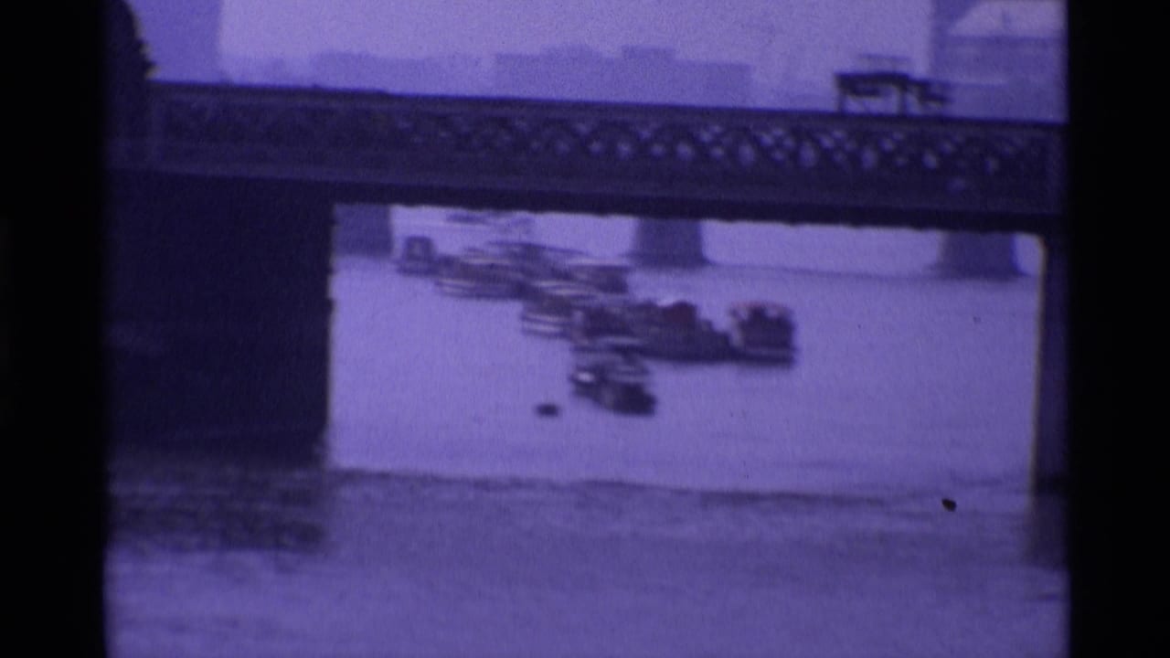 Bridge over the Thames with small boats clustered near the riverbank.