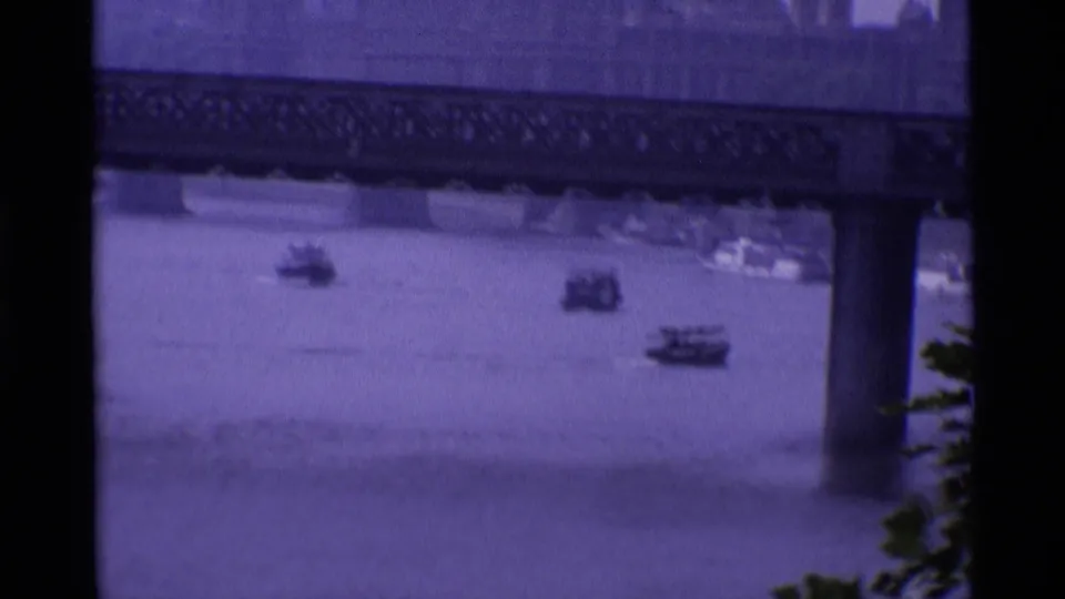 1969 London 8mm view of the River Thames with a bridge, support pier, and scattered small boats under soft exposure.