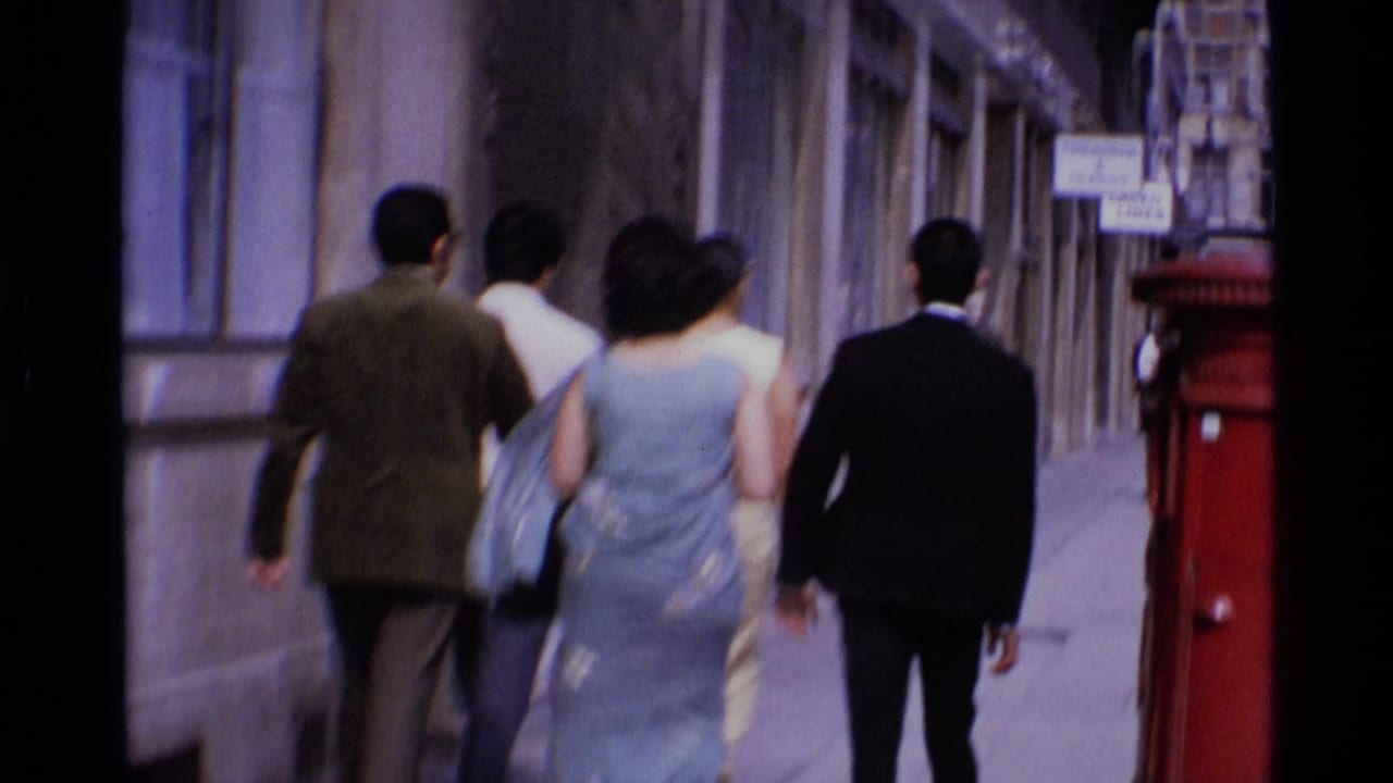 1969 London street view with adults walking away from the camera near a red British postbox on Aldwych.