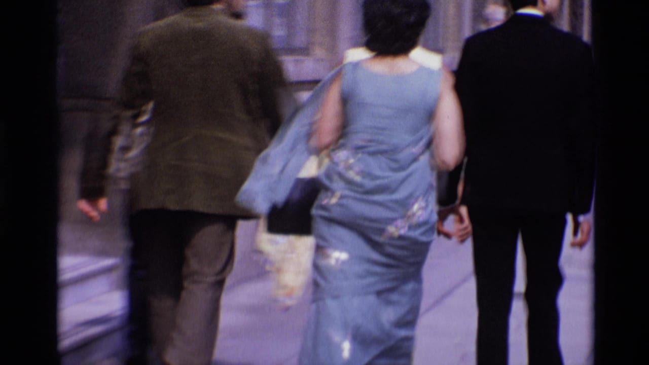 Adults walk away from the camera on a city sidewalk.