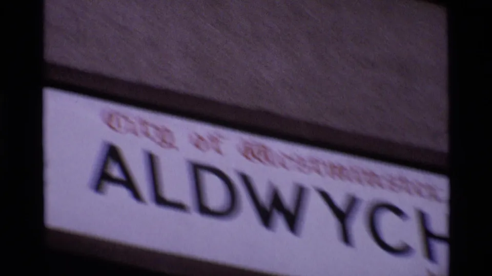 Soft-focus close-up of an Aldwych street sign in London, with the Westminster text faintly visible above it.
