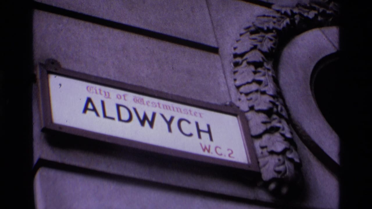 1969 London home-movie frame showing the Aldwych W.C.2 street sign on a building wall near an arched entrance.