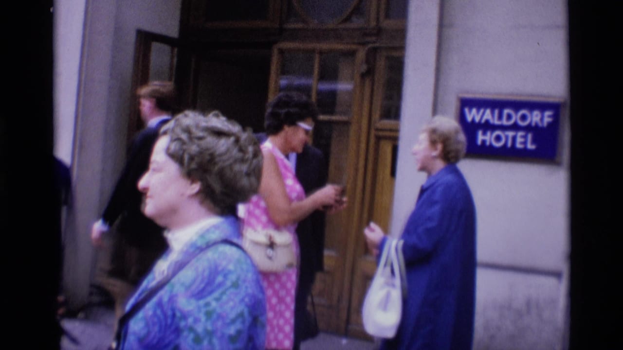 1969 London street view outside the Waldorf Hotel, with pedestrians in period clothing moving near the entrance.