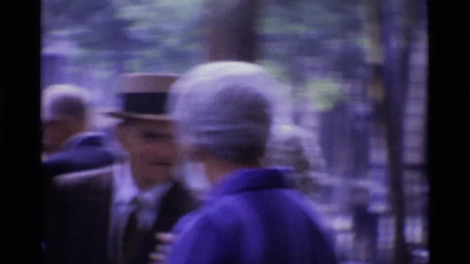 Motion-blurred 1969 London 8mm frame of pedestrians crossing the foreground on a busy sidewalk.
