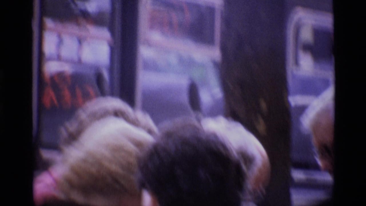 London 1969 home-movie frame showing passengers close to a bus window, with soft focus and purple 8mm color cast.