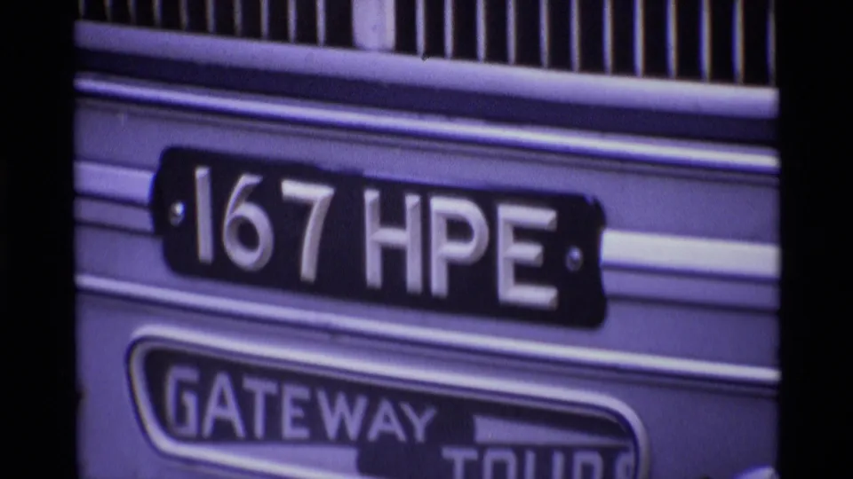 Home-movie close-up of London bus signage, with "167 HPE" above "GATEWAY TOURS" and vertical railings near the top of frame.
