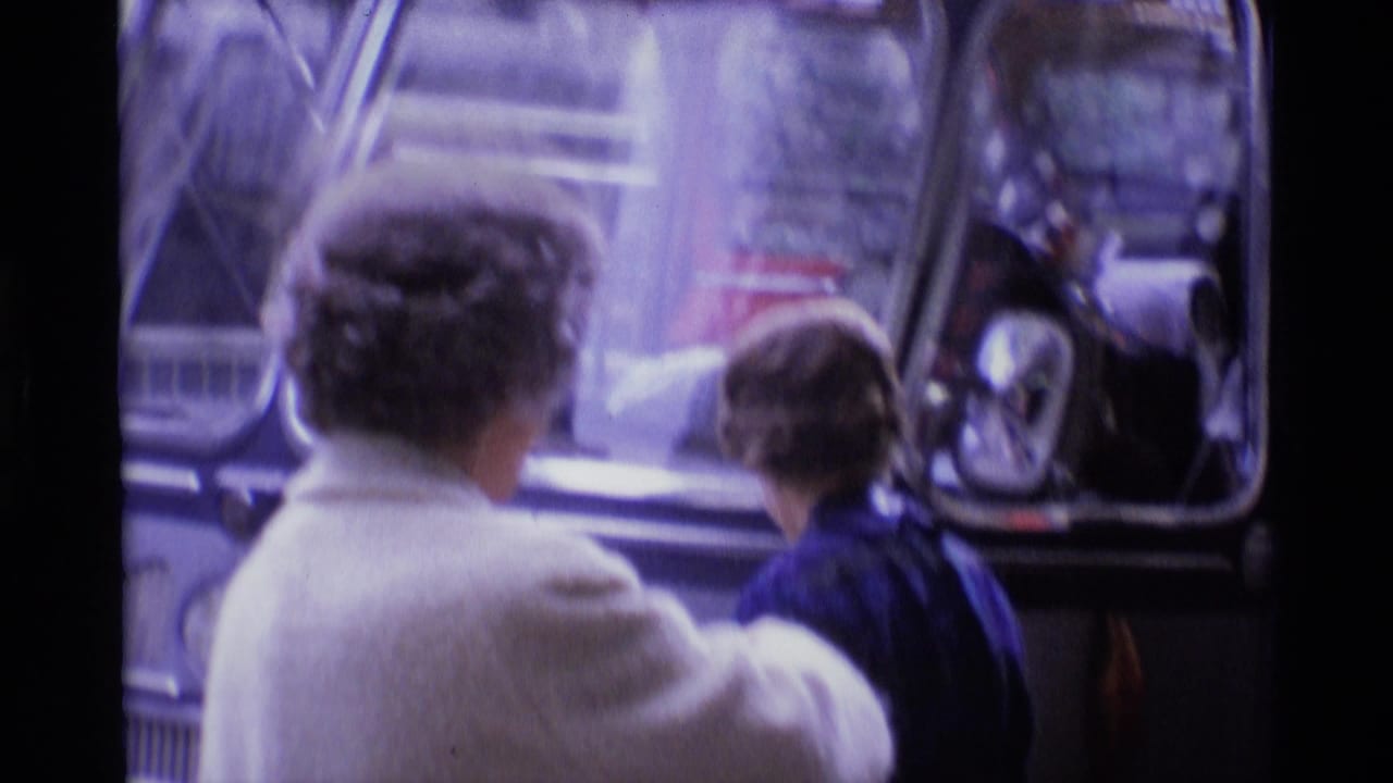 Two older passengers seen from behind near the side windows of a bus.