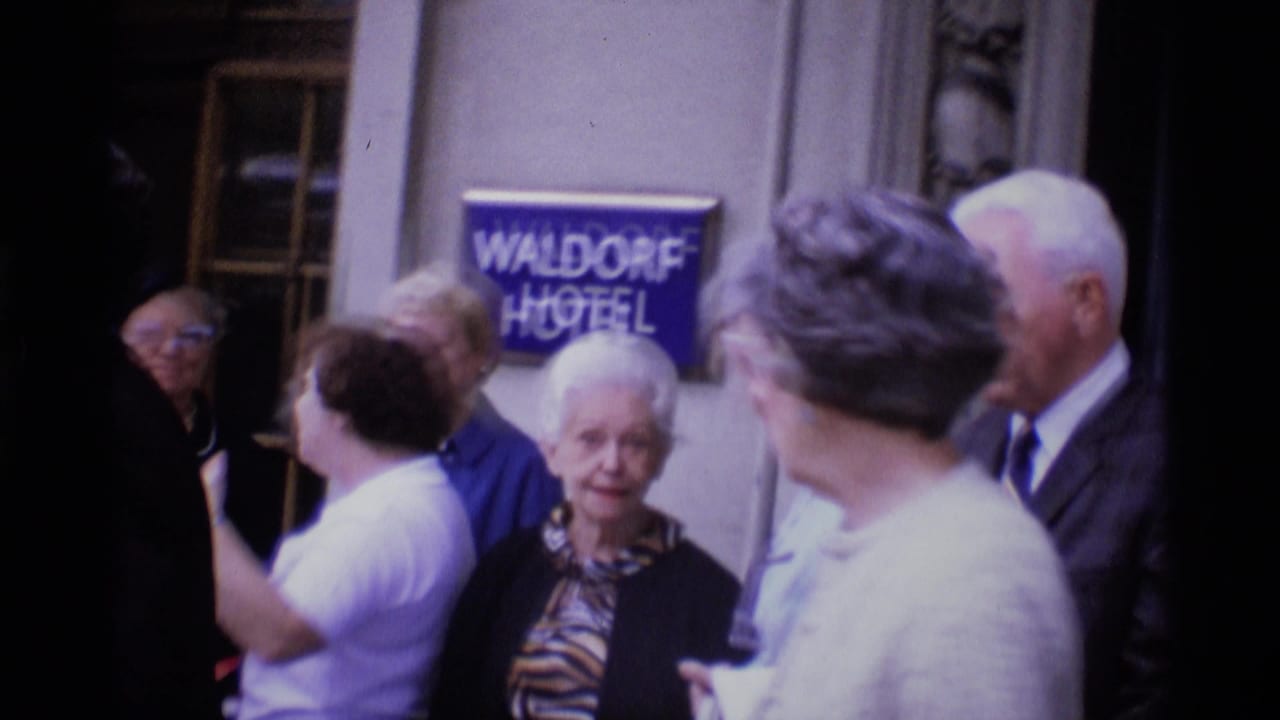 1969 London hotel entrance with several adults gathered near the blue Waldorf Hotel sign on the exterior wall.