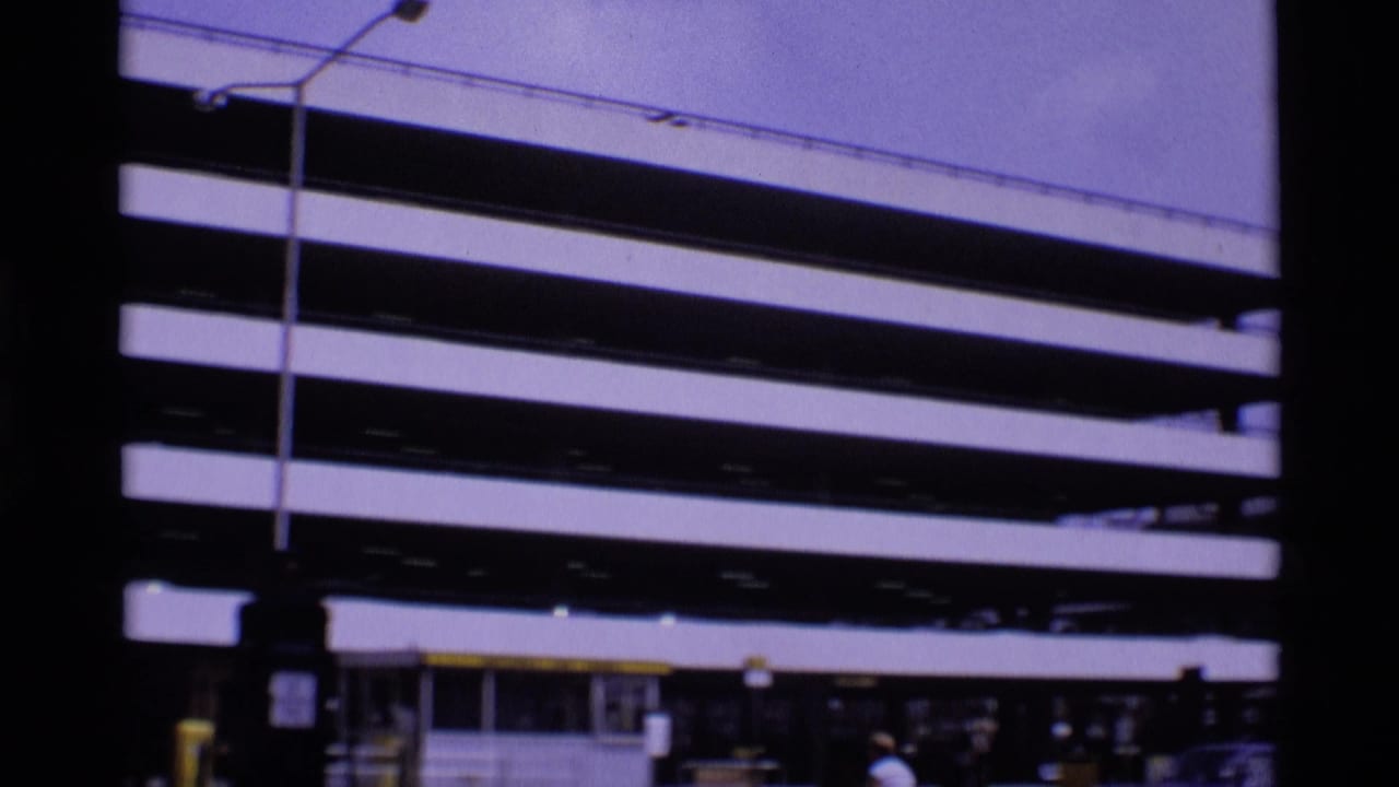 Striped multi-level parking deck with street lamps and small figures near the lower edge.